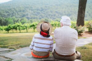 Elderly couple sitting on a bench overlooking a vineyard